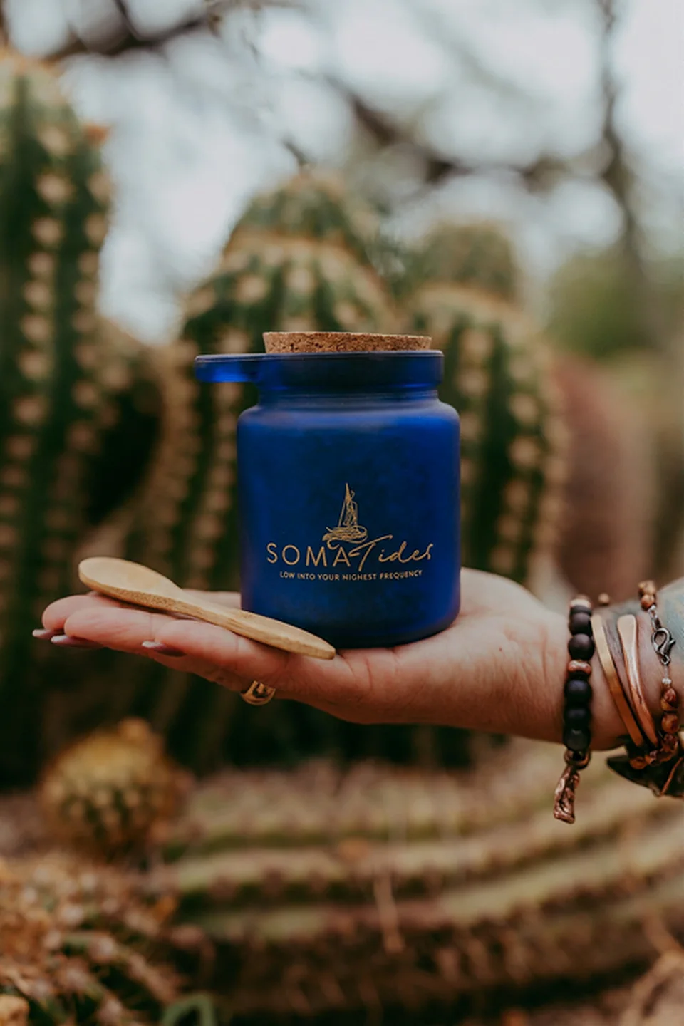 Hand holding a Soma Tides cork-lidded jar among desert cacti